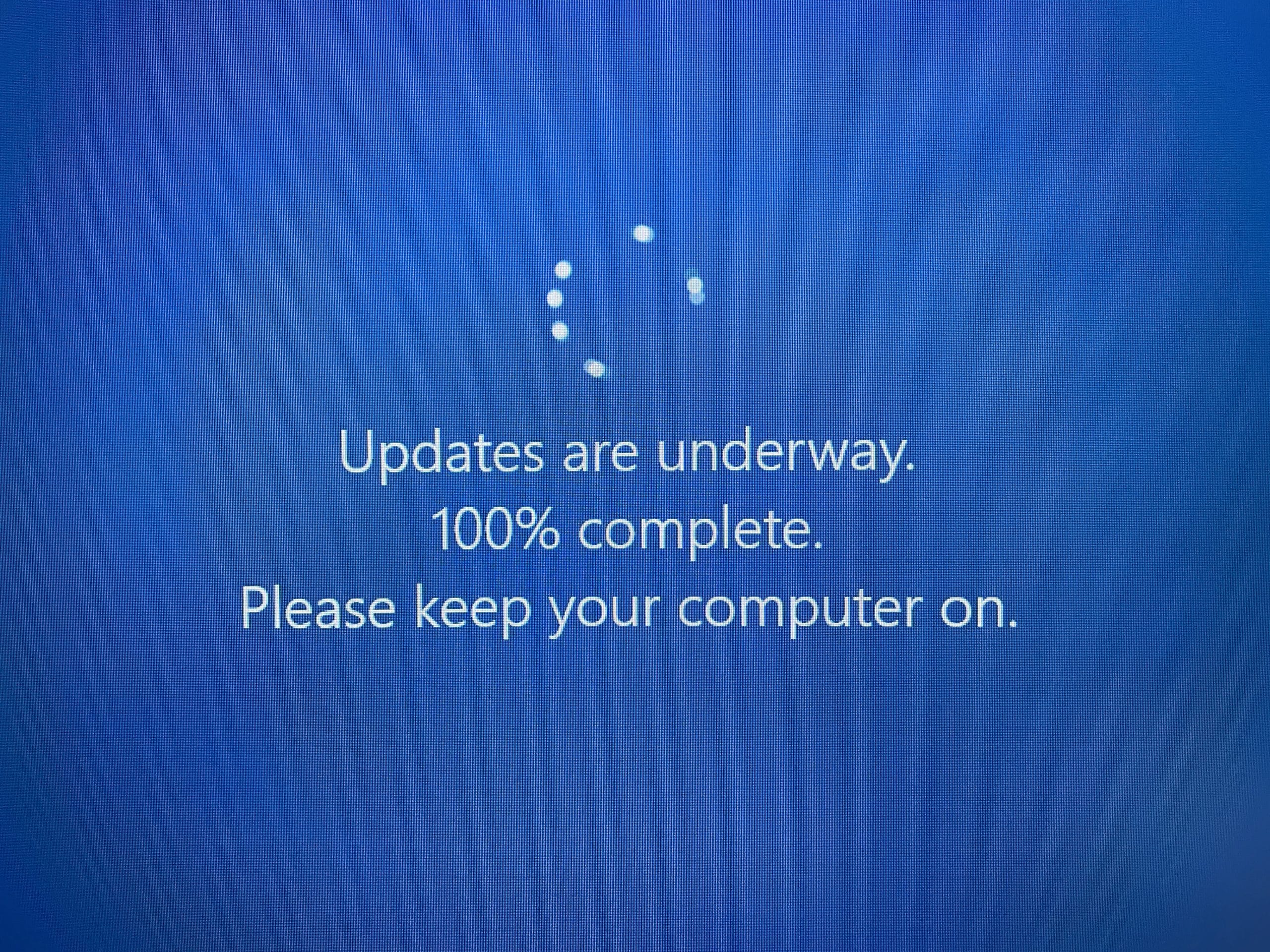 Blue screen with a loading wheel and it says "Updates are underway. 100% complete. Please keep your computer on"