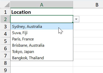 The image shows an Excel spreadsheet displaying a drop-down list in cell A2 under the header 'Location.' The list is expanded showing options such as 'Sydney, Australia,' 'Suva, Fiji,' 'Paris, France,' 'Brisbane, Australia,' 'Tokyo, Japan,' and 'Bangkok, Thailand.' The mouse cursor is hovering over the option 'Sydney, Australia.
