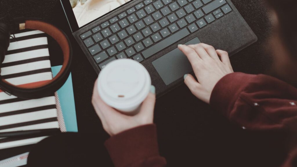 Woman working on laptop and holding a coffee