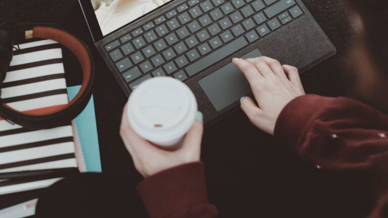 Woman working on laptop and holding a coffee